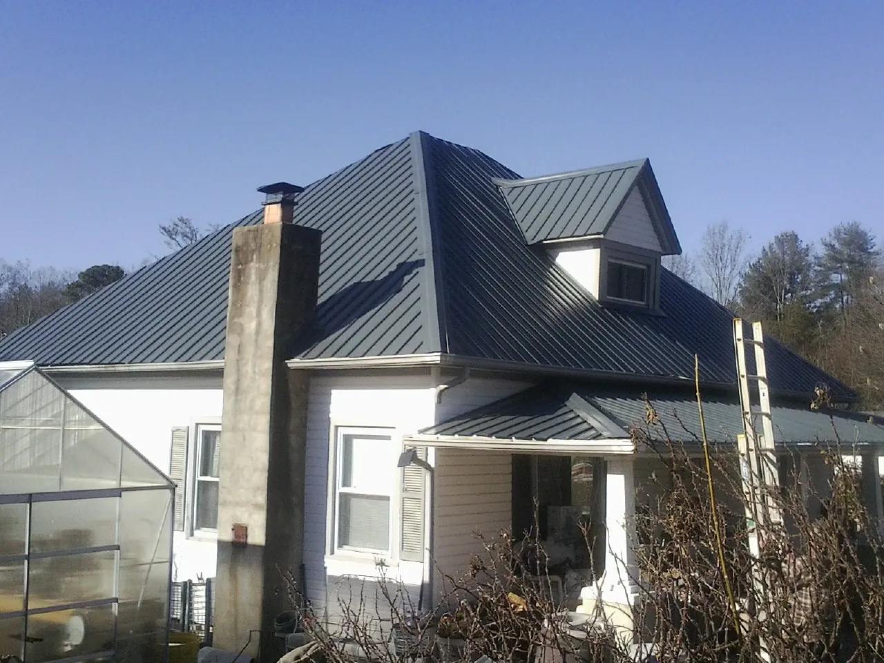 Dark blue standing seam metal roof on a white farmhouse with dormer — Slate & Tile Roof Repair by Roofing Brothers in Copperas Cove