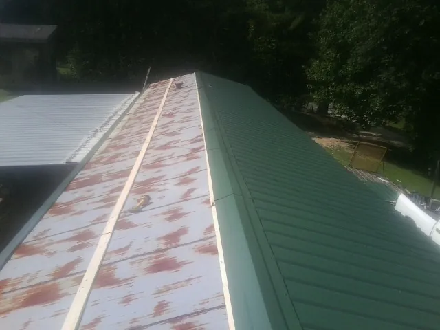 Old rusted panels beside newly installed green metal roofing — Wind Damage Roof Repair by Roofing Brothers in Copperas Cove