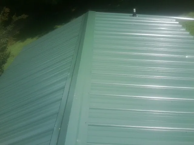New green metal panels meeting at the ridge of a roof — Flat Roof Repair work by our crew in Copperas Cove