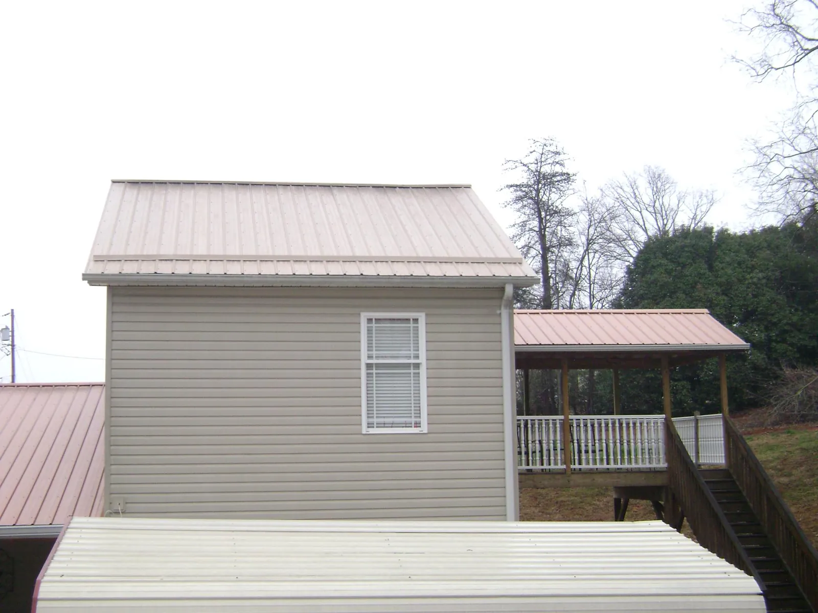 Tan metal roofs on a two story addition and attached porch, from a Roof Replacement job in Copperas Cove
