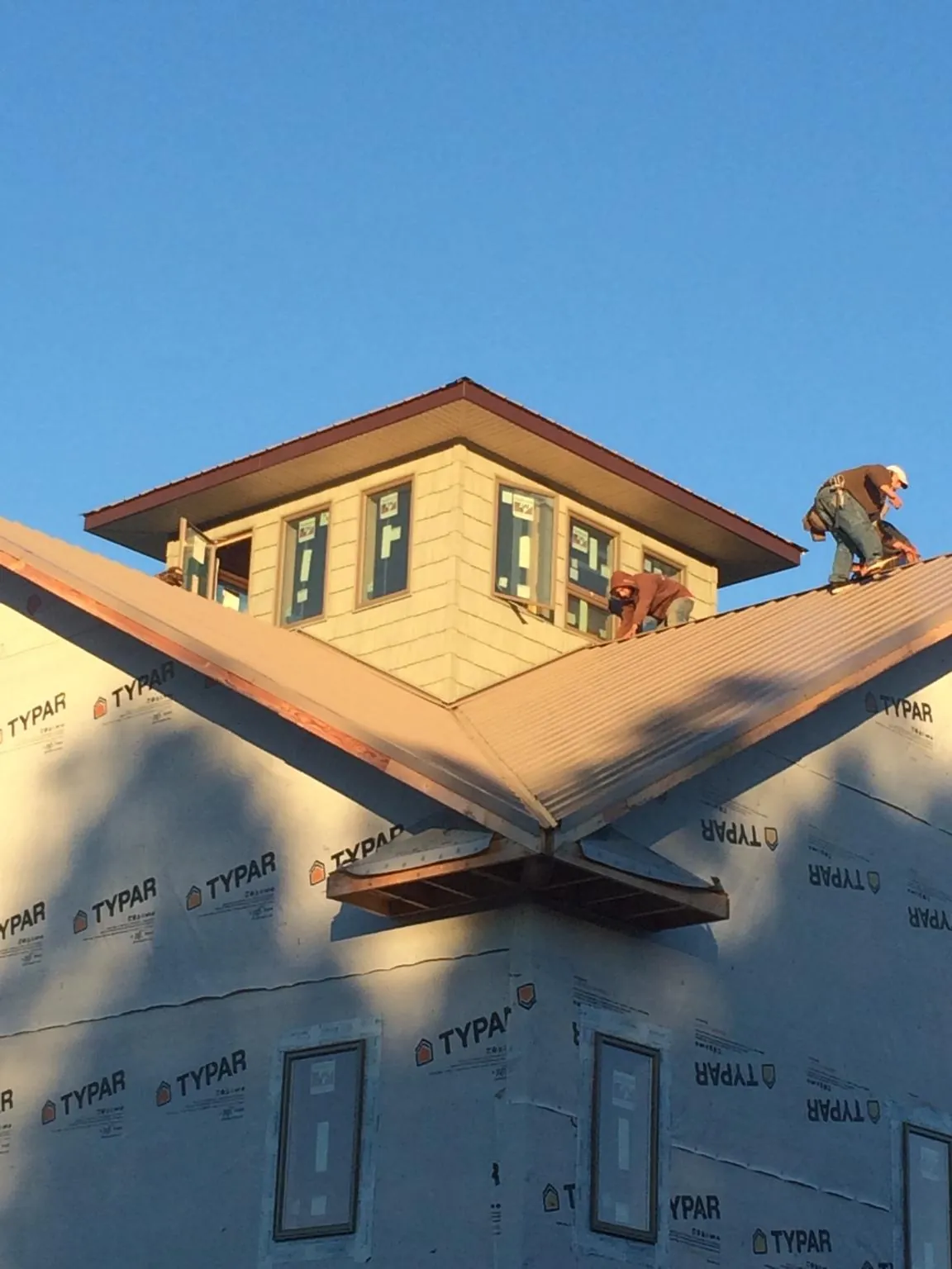 Roofers working around a rooftop cupola on a new metal roof at sunset — Roof Waterproofing in Copperas Cove by Roofing Brothers